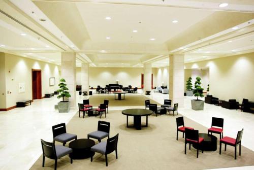 a lobby with tables and chairs and a piano at Hilton Dead Sea Resort & Spa in Sowayma