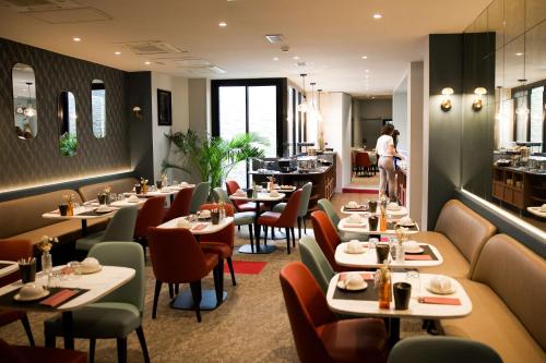 a restaurant with tables and chairs and a person in the background at Le Grand Hôtel Grenoble, BW Premier Collection by Best Western in Grenoble