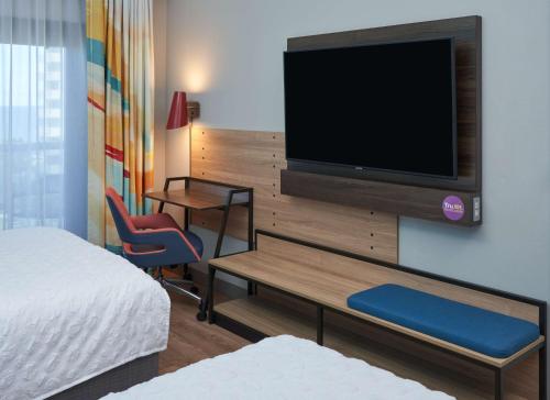 a hotel room with a bed and a television on a wall at Tru By Hilton Pompano Beach Pier in Pompano Beach
