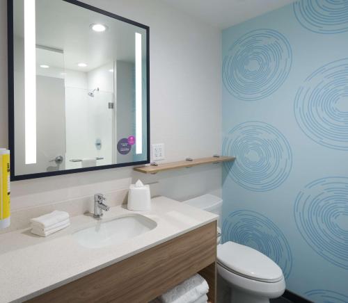 a bathroom with a sink and a toilet and a mirror at Tru By Hilton Pompano Beach Pier in Pompano Beach