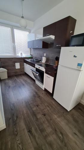 eine Küche mit einem weißen Kühlschrank und Holzböden in der Unterkunft Flower apartman in Dunajská Streda