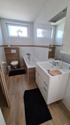 ein Badezimmer mit einem Waschbecken, einer Badewanne und einem WC in der Unterkunft Flower apartman in Dunajská Streda