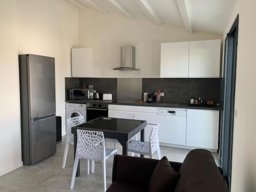 une cuisine avec une table noire et des appareils électroménagers blancs dans l'établissement Maison terrasse proche centre ville et ile de Ré, à La Rochelle