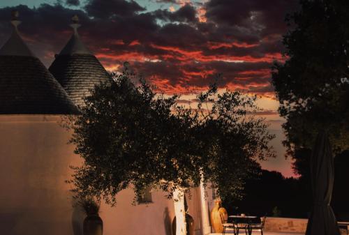 a sunset over a white building with a tree in front at Relais I Secolari in Selva di Fasano