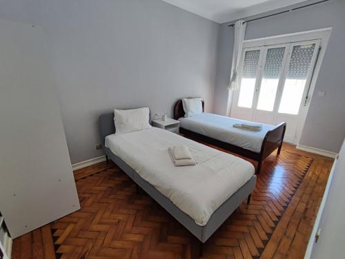 Duas camas num quarto com pisos em madeira em Lisbon traditional T2 with balcony in Damaia, Lisbon na Amadora