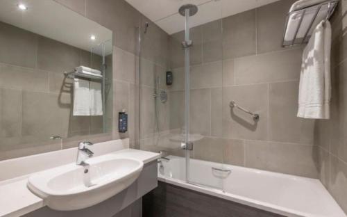 ein Badezimmer mit einem Waschbecken, einer Badewanne und einem Waschbecken in der Unterkunft Clayton Hotel Galway in Galway