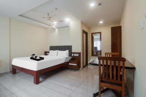 a bedroom with a white bed and a chair at Townhouse DJ Grand in Tirupati