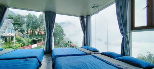 two beds in a room with large windows at Ban Mai Xanh homestay Tam Đảo in Vĩnh Phúc