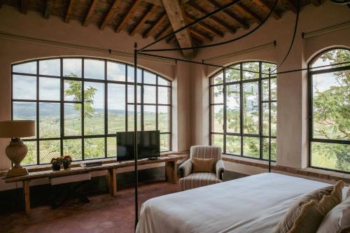 a bedroom with a bed and a tv and windows at Exclusive Wine Resort - Villa Dianella in Vinci