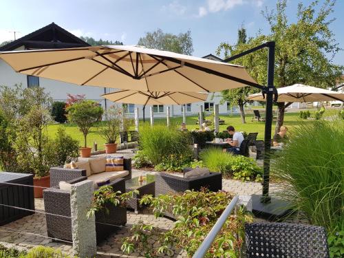 a patio with an umbrella and tables and chairs at Landhotel Sonnenhalde in Bad Boll