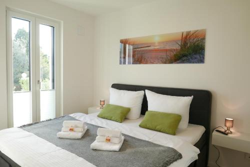 a white bed with two green pillows on it at Baabe Villen Ensemble Fewo 22 _Str in Baabe
