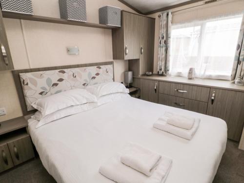 a bedroom with a large white bed with two towels on it at Flower Stone in Morpeth