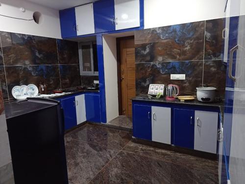 een keuken met blauwe en witte kasten in een kamer bij New Premium Fully Furnished 2 BHK Flats Near Station in Tirupati