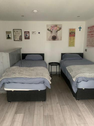 2 camas en una habitación con una cruz en la pared en Cosy open plan Cabin in Dublin 11 suit 2 persons en Dublín