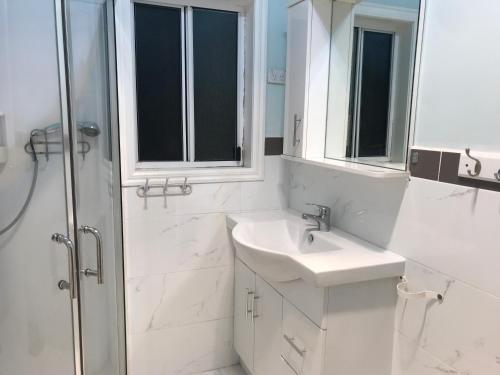 a white bathroom with a sink and a shower at A cozy place in Noble Park
