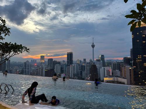a group of people in a infinity pool with a city skyline at The Axon Suites Bukit Bintang KLCC By SKYSCRAPER in Kuala Lumpur