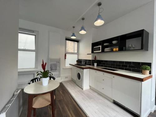 uma cozinha com armários brancos, uma mesa e um lavatório em Glasshouse yard studio's F1 em Londres