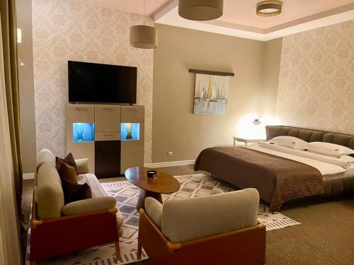 a bedroom with a bed and a tv and chairs at Villa-Sofia Mini-hotel in Odesa