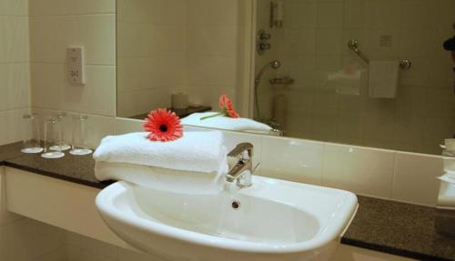 a bathroom sink with a red flower on top of it at Maldron Hotel & Leisure Centre Limerick in Limerick