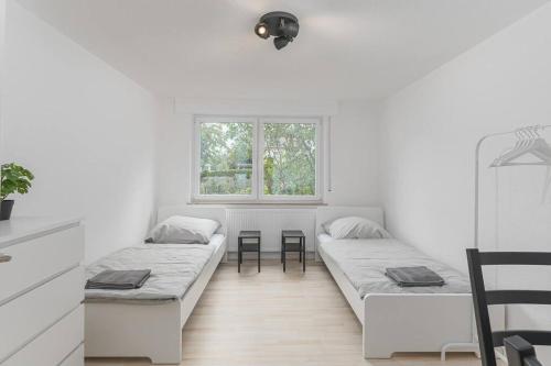a white room with two beds and a window at NT01 schönes Appartement - ideal für Teams Self Check-In in Nürtingen