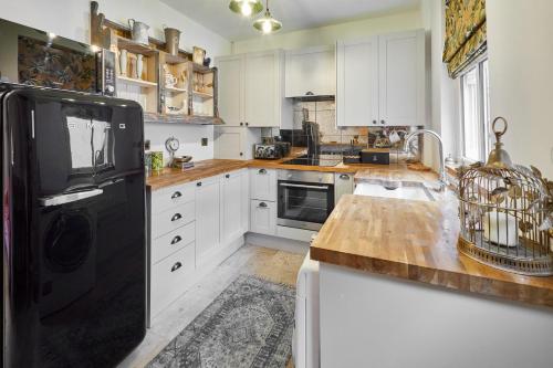 cocina con armarios blancos y nevera negra en Beautiful 2-Bed Victorian House in Stamford, en Stamford