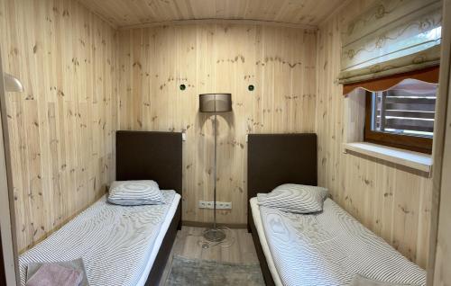 two beds in a room with wooden walls at Atostogų namelis in Kurėnai