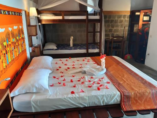 a bedroom with a bed with red rose petals on it at Libertalia Hotel in Sainte Marie