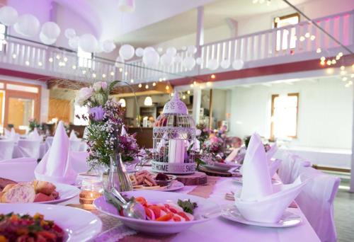 une grande table avec des assiettes blanches de nourriture et de fleurs dans l'établissement Schmidts, à Herbstein