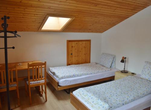 Habitación con 2 camas, mesa y tragaluz. en Hotel Grimsel en Obergesteln