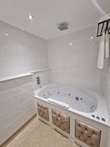 a white bathroom with a large tub in it at RainHill Hall Hotel in Rainhull