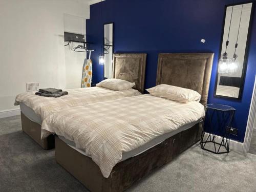 um quarto com 2 camas e uma parede azul em Amazing 2 Bedrooms House em Bridgend