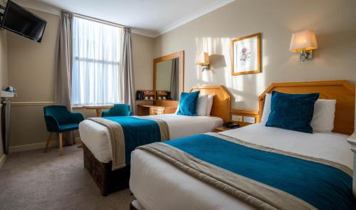 um quarto de hotel com duas camas e uma televisão em Harcourt Hotel em Dublin