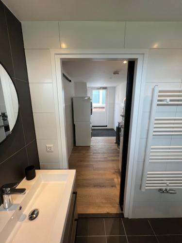 een badkamer met een wastafel en een koelkast bij Luxe woning ‘BARNS’ Castricum aan Zee + airco + parkeren in Castricum