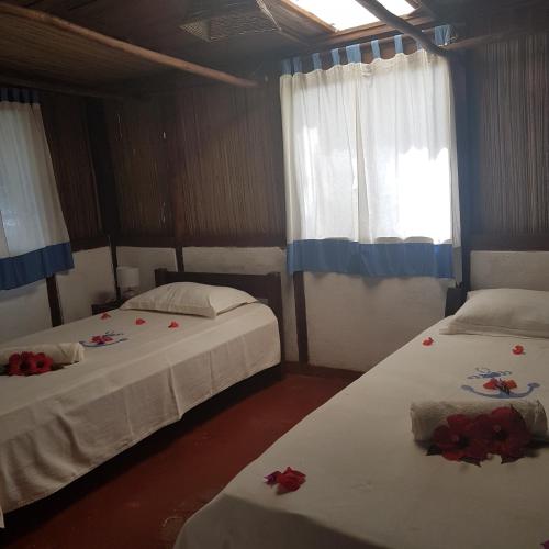 two beds in a room with red roses on them at Libertalia Hotel in Sainte Marie