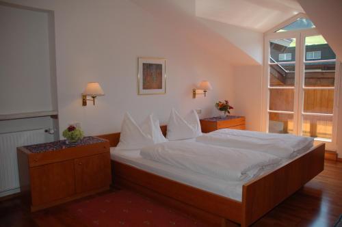 a bedroom with a bed with white sheets and a window at Hotel Rauscher und Paracelsus in Bad Hofgastein