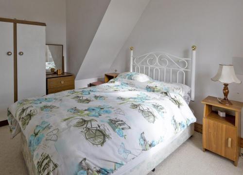 - une chambre avec un lit blanc et un couvre-lit floral dans l'établissement Matthews Traditional Holiday Cottage by Trident Holiday Homes, à Doonbeg