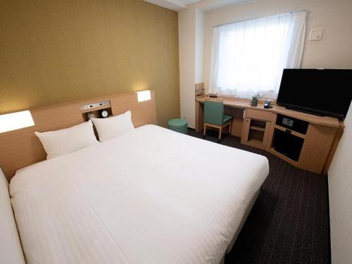 大阪市にあるライズホテル大阪なんばの大型ベッドとテレビが備わるホテルルームです。