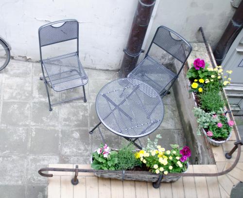 two chairs and a table and flowers on a patio at Red Nose Hostel with Self-Check In in Rīga