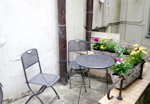 two chairs and a table on a balcony with flowers at Red Nose Hostel with Self-Check In in Rīga