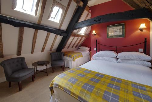 ein Schlafzimmer mit 2 Betten und 2 Stühlen im Dachgeschoss in der Unterkunft Corinium Hotel & Restaurant in Cirencester