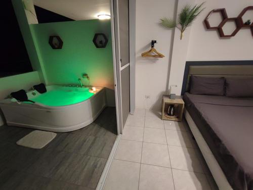 a bathroom with a green tub and a couch at Bonsai Jacuzzi Suites in Panglao Island