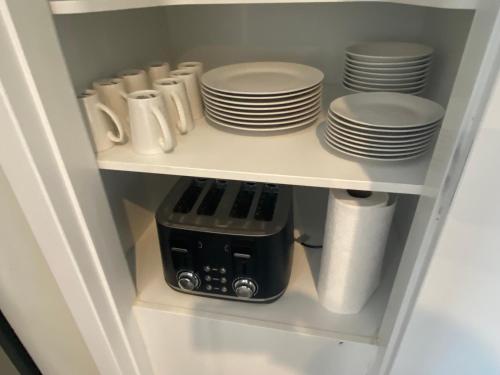 a white cabinet with plates and dishes in it at Hamilton Hospital Retreat - 2 Bedroom Townhouse Modern Warm Quiet in Hamilton