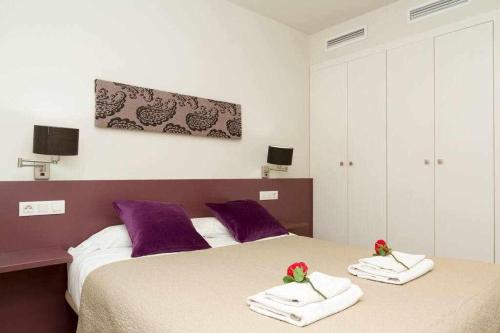 um quarto com duas camas com toalhas e flores em Port V Apart centrico con estilo 21 em Barcelona