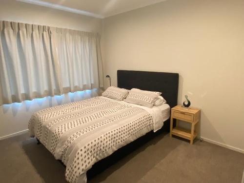 a bedroom with a bed with a white comforter and a window at Hamilton Hospital Retreat - 2 Bedroom Townhouse Modern Warm Quiet in Hamilton