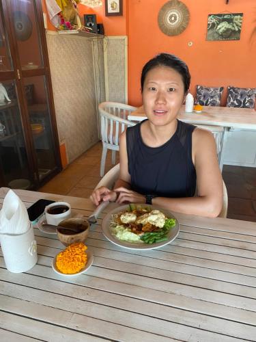 een vrouw die aan een tafel zit met een bord eten bij Wahyu Accomodation in Ubud
