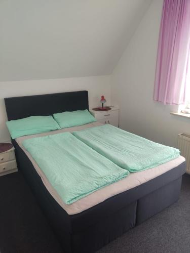 a bedroom with a bed with green sheets and a window at Pokoje Gościnne U Dany in Jarosławiec