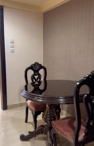 a wooden table and a chair and a table and a wall at Levant Hotel فندق قصر المشرق in Najran