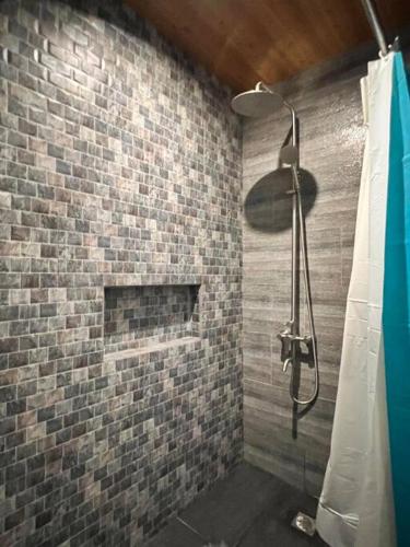 a shower in a bathroom with a brick wall at Modern Unit Near The Beach at Canyon Cove Nasugbu in Nasugbu