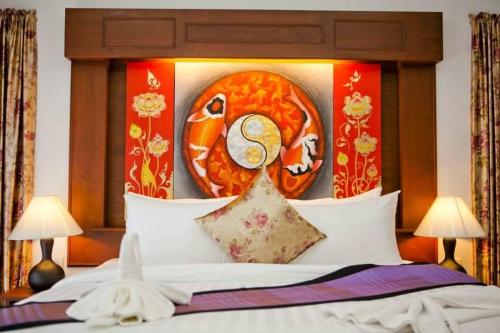 a bedroom with a bed with a painting on it at Baan Chong Fa Resort in Khao Lak