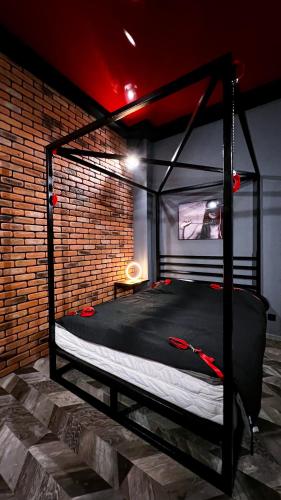 a black bed in a room with a brick wall at BDSM Red Room Apartment in Łódź